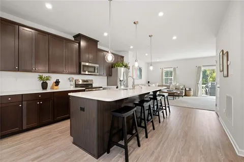 a kitchen with a table chairs wooden floors and a view of living room