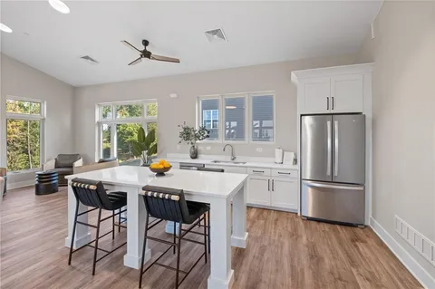 a kitchen with stainless steel appliances a dining table chairs refrigerator and sink