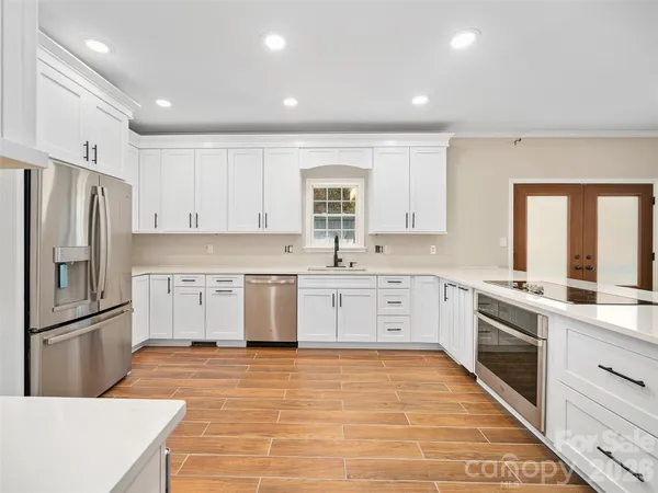 a large kitchen with stainless steel appliances cabinets a sink and a window