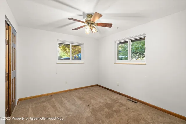 an empty room with windows and fan
