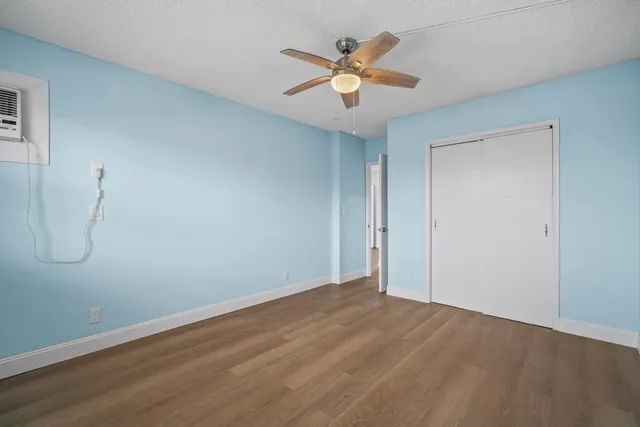 a view of a room with wooden floor and a ceiling fan
