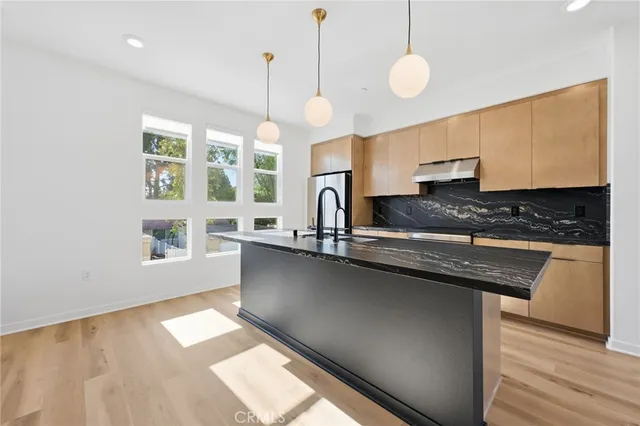 a kitchen with granite countertop a stove a sink and white cabinets with wooden floor