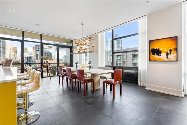 a view of a dining room with furniture a chandelier and large windows