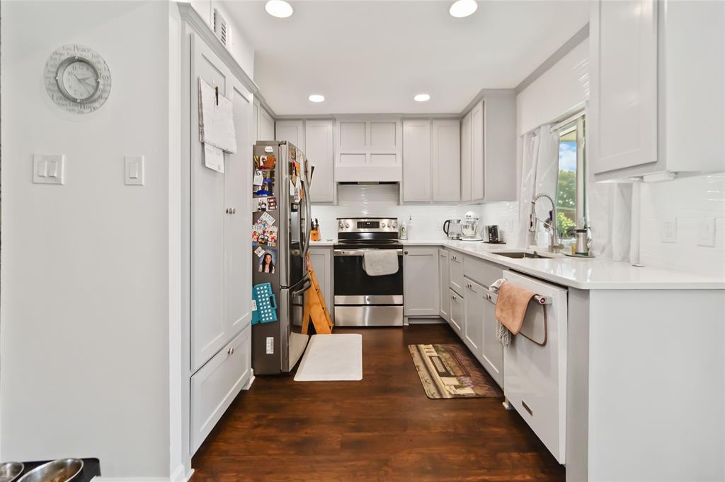 1920 Avignon Court Carrollton, TX 75007 - Photo 13 of 31 Kitchen featuring stainless steel appliances, dark wood-style flooring, recessed lighting, light stone counters, and tasteful backsplash