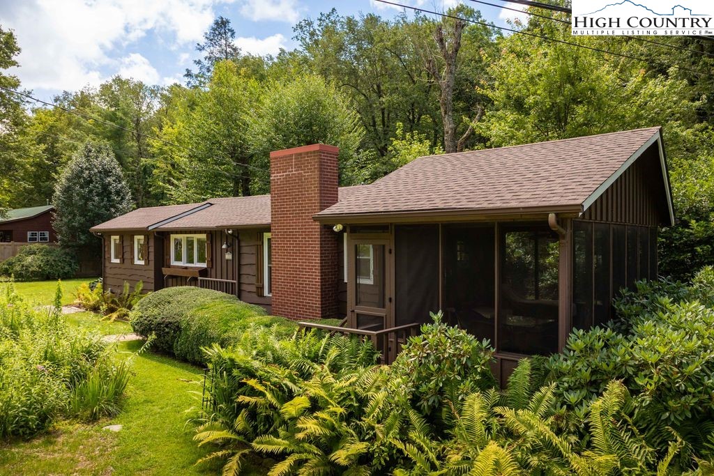 a view of a house with a small yard plants and large tree