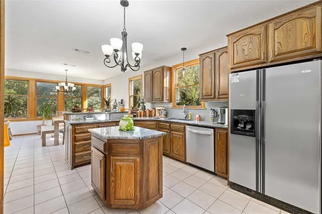a kitchen with stainless steel appliances granite countertop a refrigerator a sink dishwasher stove and oven