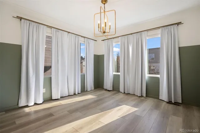 an empty room with wooden floor windows and entryway