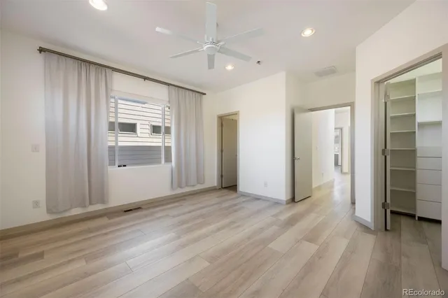 an empty room with wooden floor cabinet and windows