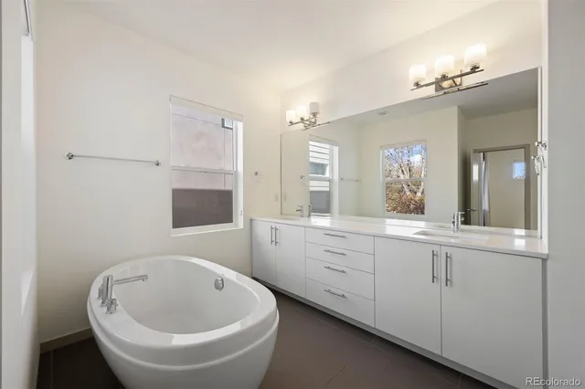 a bathroom with a white tub shower vanity and a sink