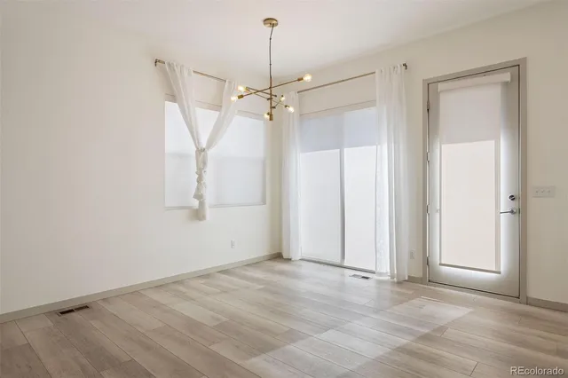 an empty room with chandelier fan and windows