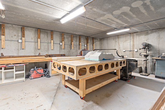 912 North Loafer Canyon Road Elk Ridge, UT 84651 - Photo 44 of 98 Concrete walls and ceiling, fluorescent lighting, concrete flooring, built-in shelving, and a mobile wooden workbench
