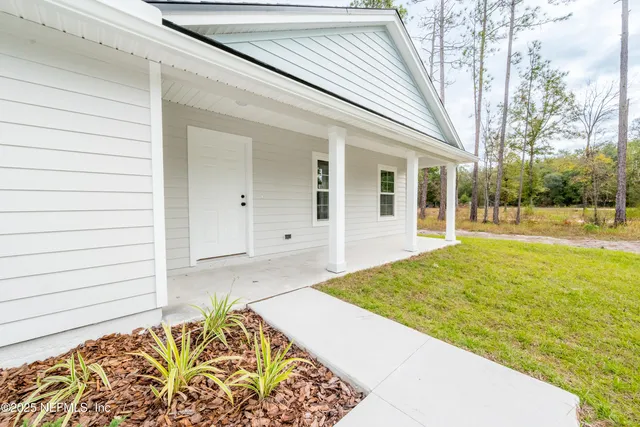 front view of a brick house with a yard and large trees