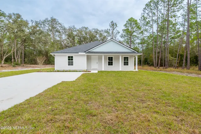 a view of a house with a yard and large trees