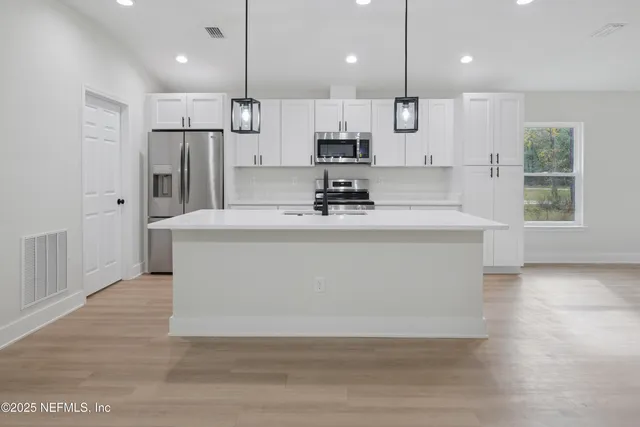 an empty room with wooden floor closet and windows