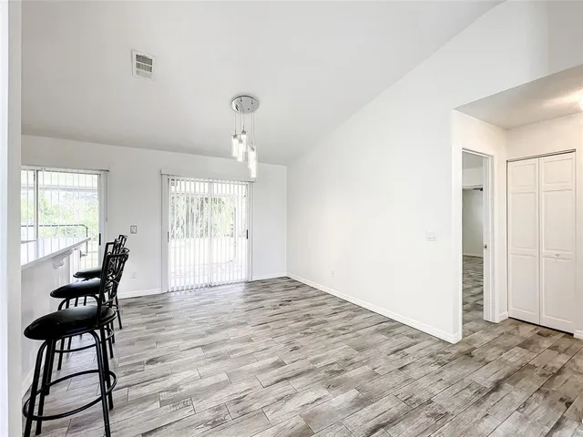 a kitchen with stainless steel appliances kitchen island granite countertop a refrigerator a stove a sink dishwasher and white cabinets with wooden floor