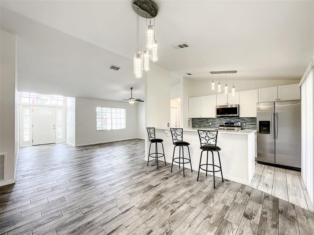 2887 Southwest Ann Arbor Road Port St. Lucie, FL 34953 - Photo 14 of 31 a kitchen with stainless steel appliances kitchen island granite countertop a refrigerator a stove a sink dishwasher and white cabinets with wooden floor
