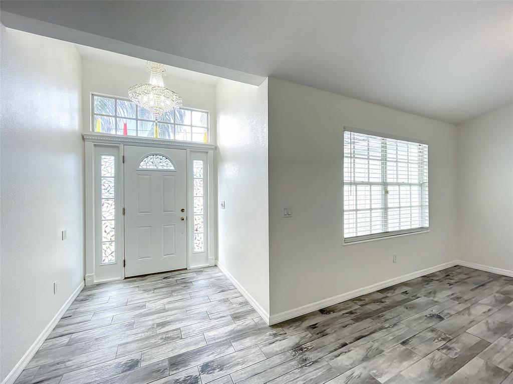 2887 Southwest Ann Arbor Road Port St. Lucie, FL 34953 - Photo 6 of 31 an empty room with wooden floor a chandelier and windows