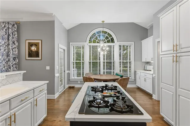 a large white kitchen with stainless steel appliances granite countertop a stove a refrigerator and wooden cabinets