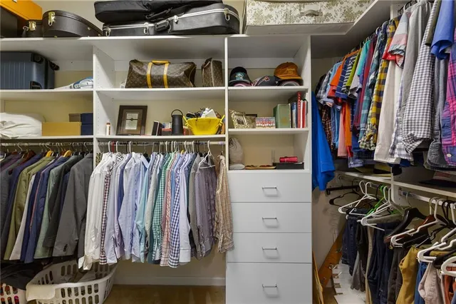 a view of walk in closet with clothes and shoes