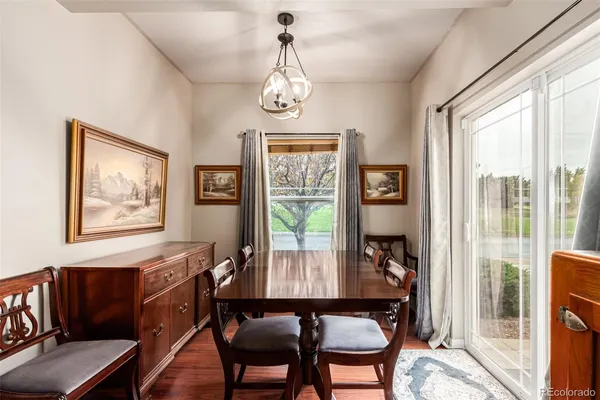 a dining room with wooden floor a chandelier a glass table and chairs