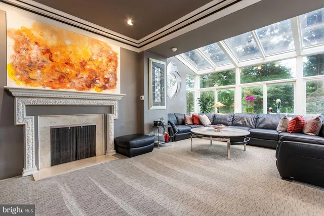 a living room with furniture a fireplace and floor to ceiling windows