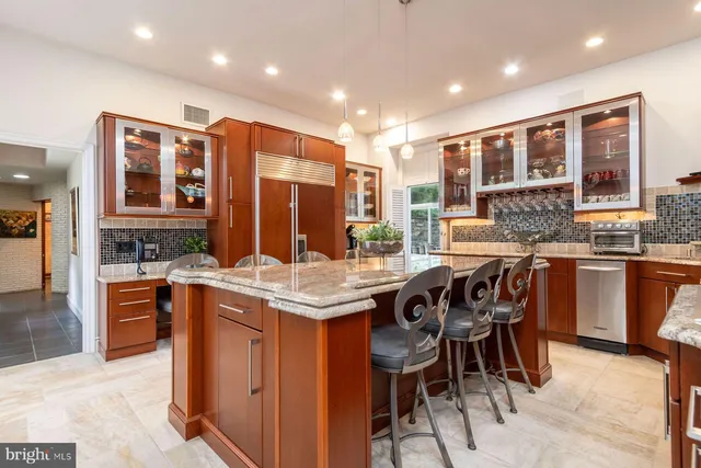 a kitchen with stainless steel appliances granite countertop a stove top oven a sink a dining table and chairs