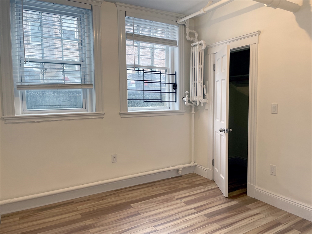 15 Thatcher Street, Unit B Brookline, MA 02446 - Photo 7 of 8 an empty room with wooden floor and windows