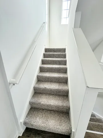 a view of staircase with white walls and a window
