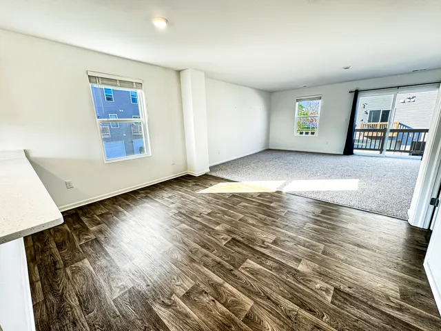 a view of an empty room with window and wooden floor