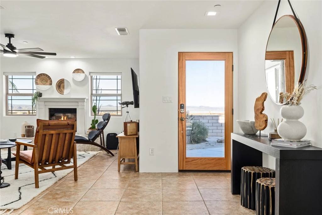 7030 Mile Square Road Joshua Tree, CA 92252 - Photo 11 of 58 a living room with furniture a fireplace and a large window