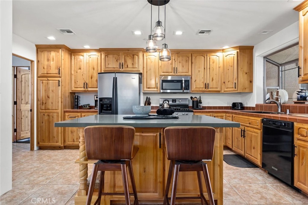 7030 Mile Square Road Joshua Tree, CA 92252 - Photo 18 of 58 a kitchen with stainless steel appliances granite countertop counter space a sink and a refrigerator