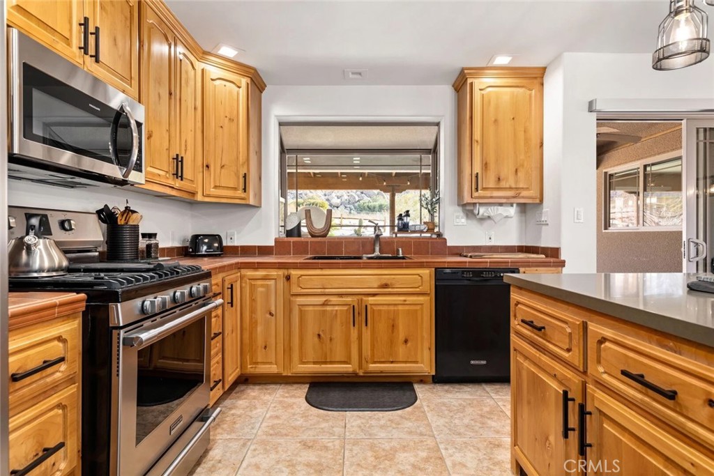 7030 Mile Square Road Joshua Tree, CA 92252 - Photo 19 of 58 a kitchen with stainless steel appliances granite countertop a stove a sink and a microwave