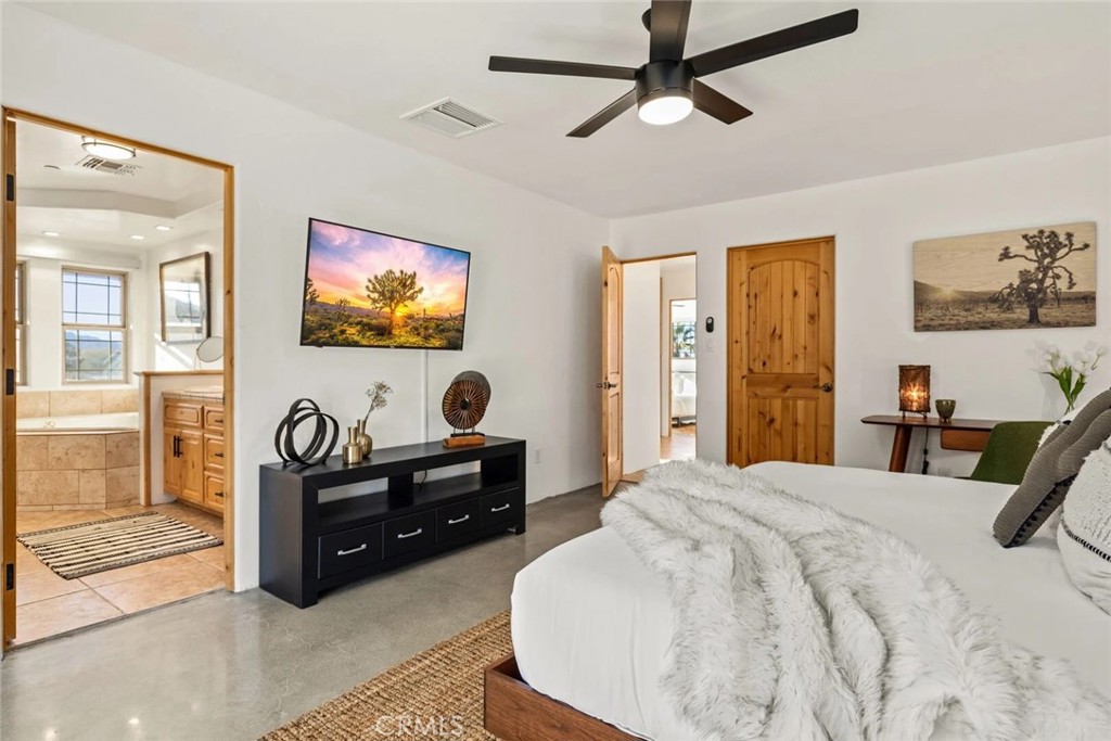 7030 Mile Square Road Joshua Tree, CA 92252 - Photo 23 of 58 a bedroom with a bed and a flat screen tv