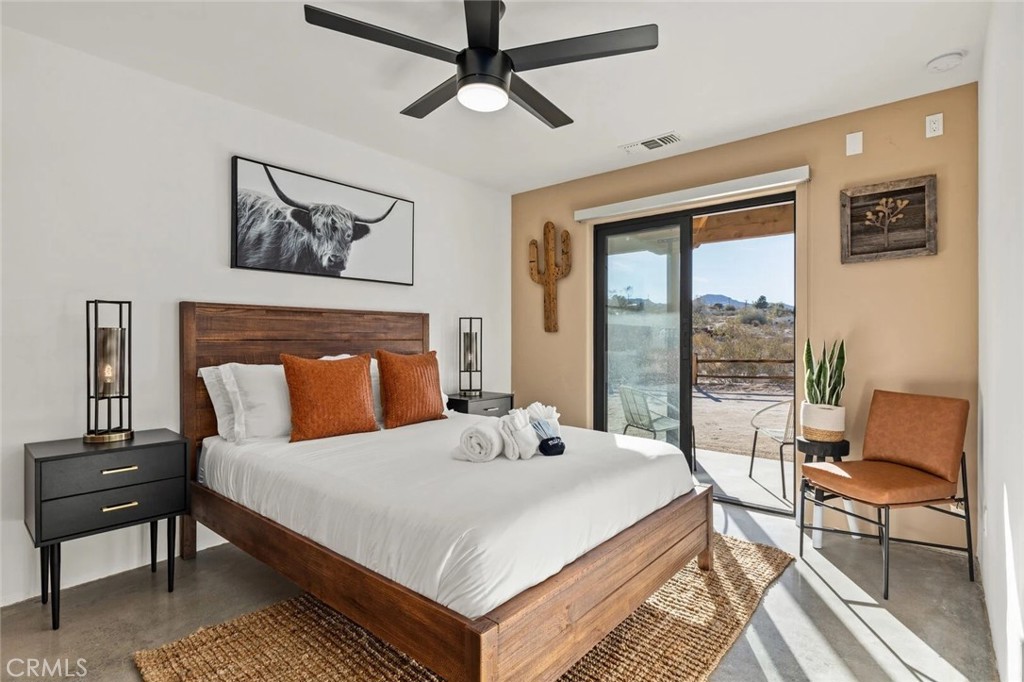 7030 Mile Square Road Joshua Tree, CA 92252 - Photo 32 of 58 a bedroom with a bed a couch and a large window