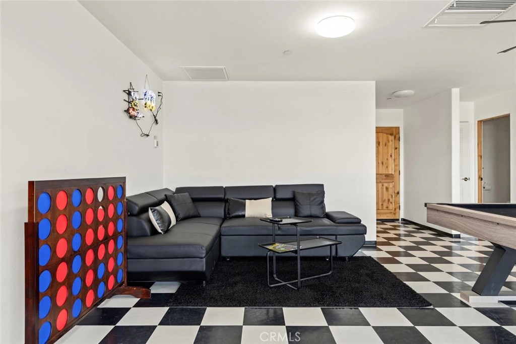 7030 Mile Square Road Joshua Tree, CA 92252 - Photo 39 of 58 a living room with a black white checkered floor with a gaming machine and a rug