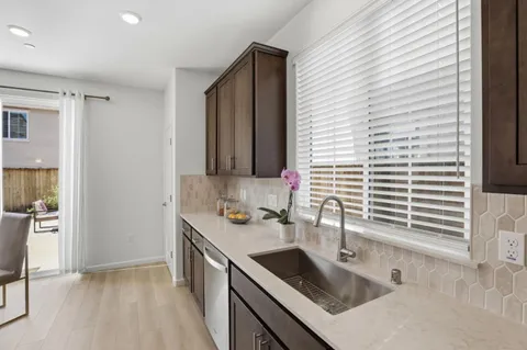 a kitchen with stainless steel appliances a sink a stove a refrigerator cabinets and wooden floor