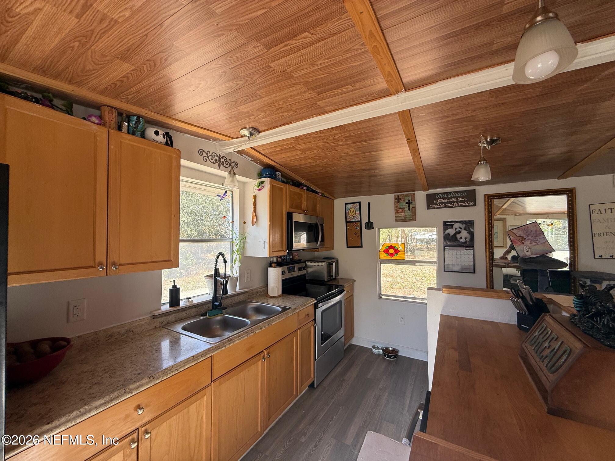 104 Churchill Street Interlachen, FL 32148 - Photo 13 of 24 a kitchen with stainless steel appliances a stove a sink dishwasher and cabinets with wooden floor