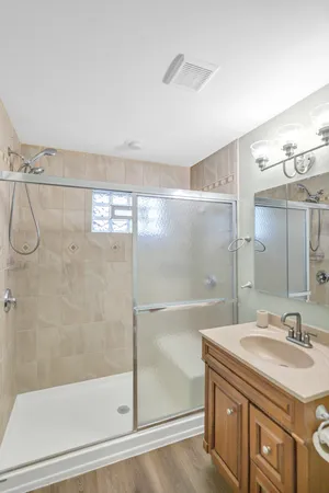 a bathroom with a granite countertop sink a mirror and a shower