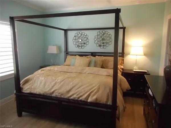 a bedroom with a bed and painting on the wall