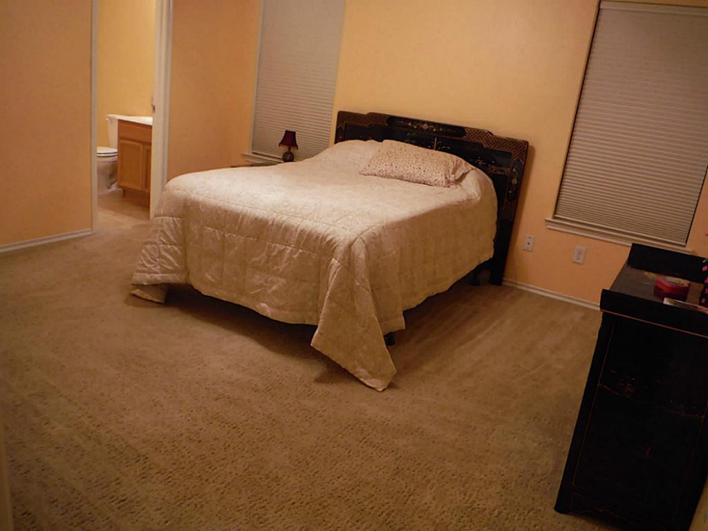 3142 Aspen Fair Trail Spring, TX 77389 - Photo 14 of 22 Cozy primary bedroom with beige walls and carpet and an en-suite bathroom. The room is softly lit with window blinds.