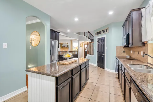 a kitchen with stainless steel appliances granite countertop a sink a stove and a wooden floors