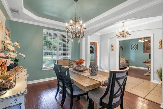 a dining room with furniture a chandelier and wooden floor