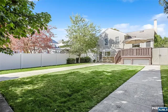 a view of a house with a yard and a large tree