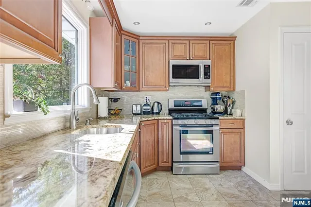 a kitchen with stainless steel appliances granite countertop a stove a sink and a microwave