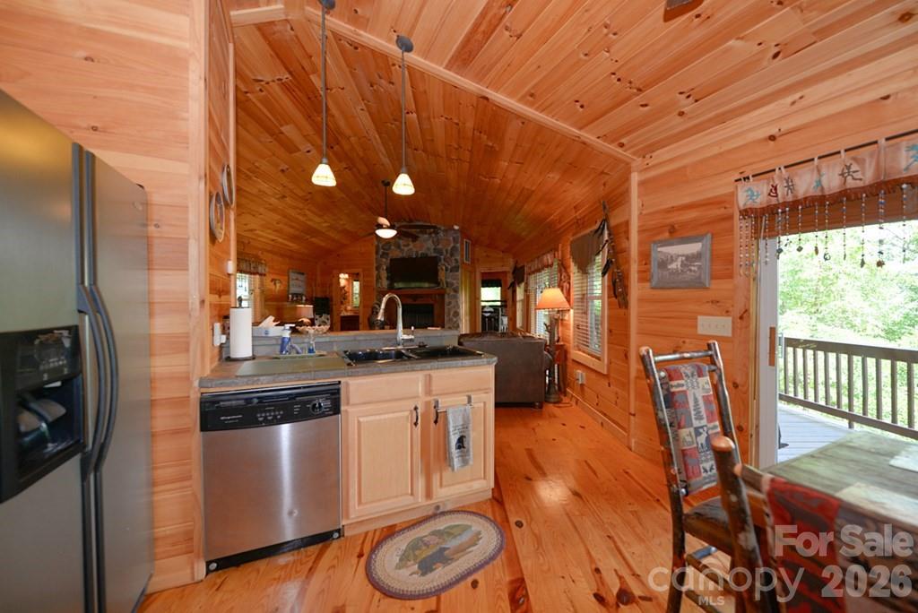 470 Bear Ridge Road Tuckasegee, NC 28783 - Photo 16 of 28 a kitchen with stainless steel appliances granite countertop a sink a stove a refrigerator white cabinets and wooden floor