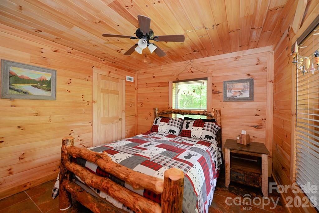 470 Bear Ridge Road Tuckasegee, NC 28783 - Photo 22 of 28 a bedroom with a bed and a chandelier