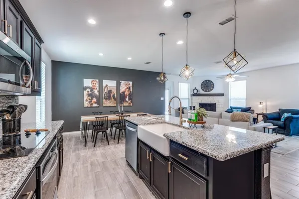 a kitchen with a stove a kitchen island a dining table and chairs with wooden floor