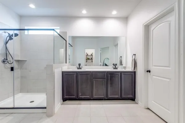a bathroom with a mirror a double vanity sink and glass door shower