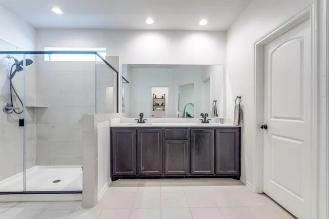 a bathroom with a mirror a double vanity sink and glass door shower