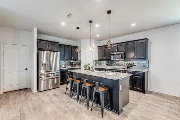 a large kitchen with cabinets wooden floor and stainless steel appliances